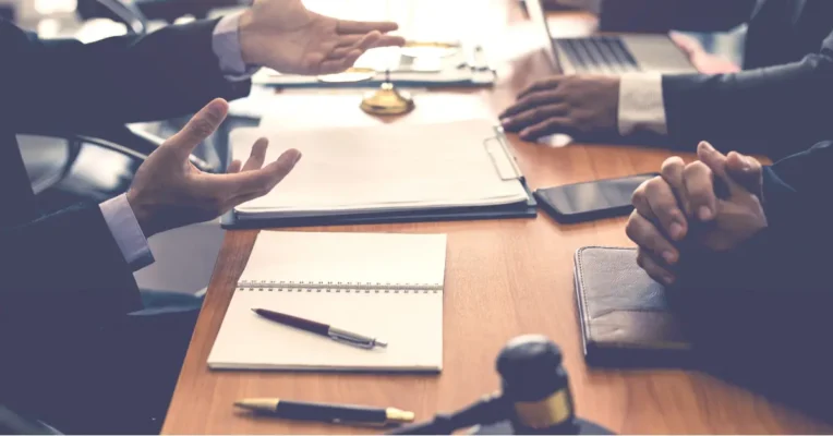 Estate lawyers discussing legal paperwork at a desk with open notebooks and a gavel