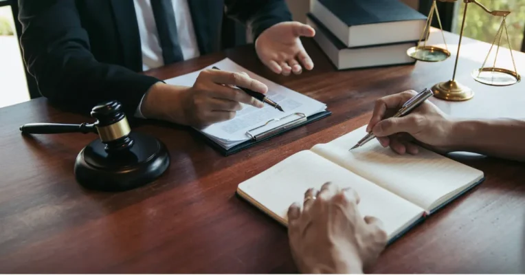 Estate lawyer and client reviewing documents at a desk with a gavel and scales of justice