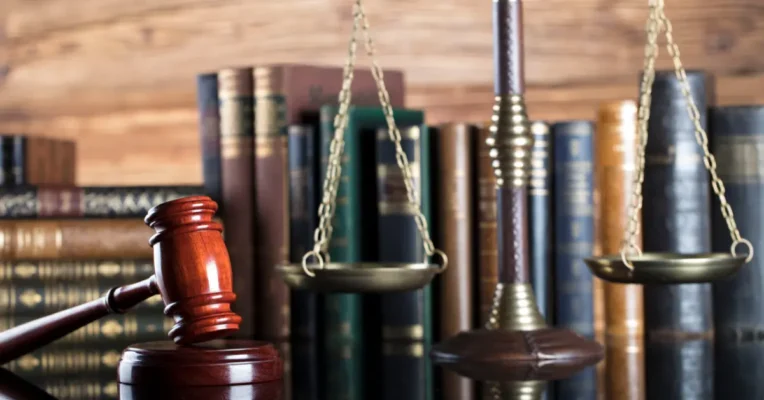 Gavel and scales of justice placed in front of law books on a wooden desk