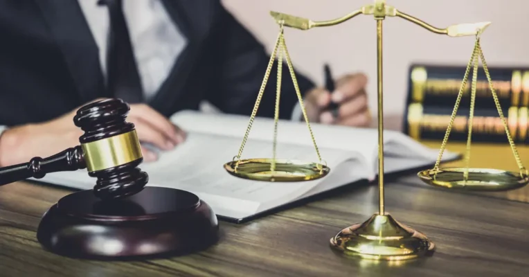 Scales of justice and a gavel on a desk as a estate lawyer works in the backgroun