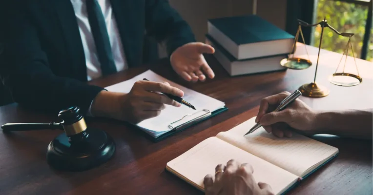 Probate lawyer consulting with a client, with scales of justice, a gavel, and legal books on the desk.