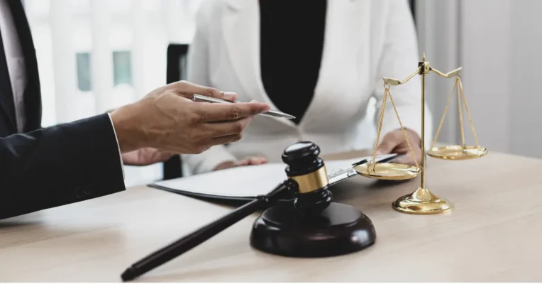 Probate lawyer holding a pen and discussing legal documents with a client, with a gavel and scales nearby