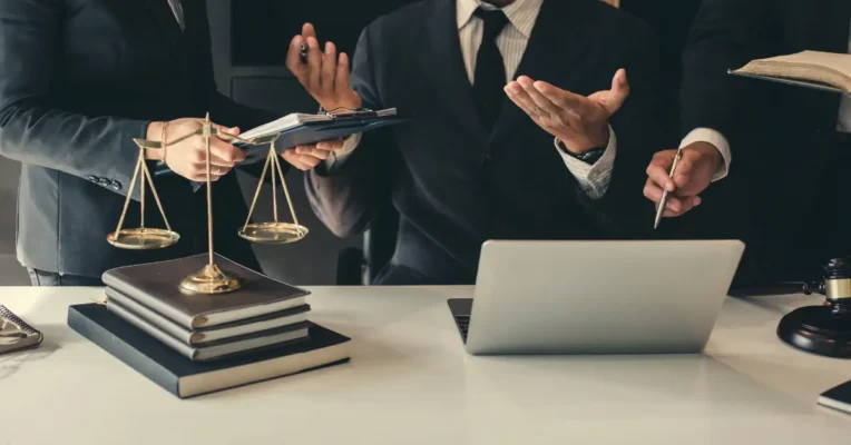 Estate lawyers discussing a case with a laptop, documents, and scales of justice on the desk