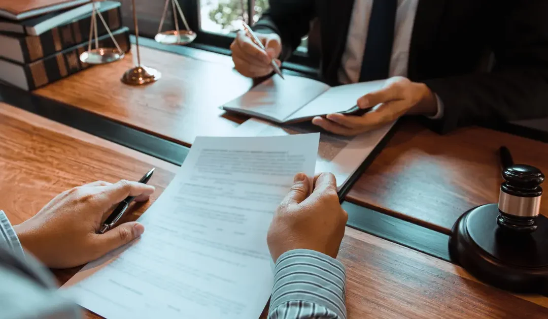 Estate lawyer and client reviewing a legal document with a gavel and scales of justice on the desk.