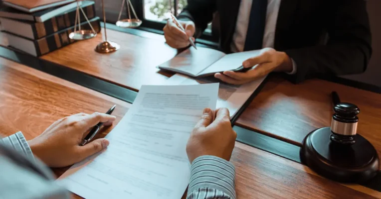 Estate lawyer and client reviewing a legal document with a gavel and scales of justice on the desk.