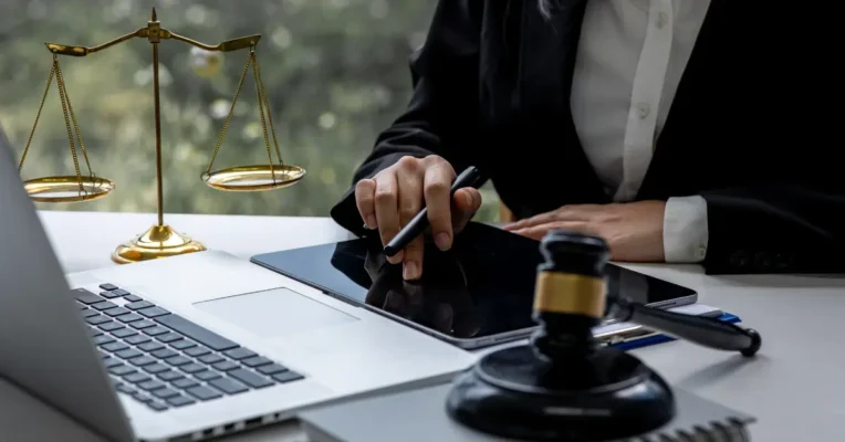 Estate planning attorney using a digital tablet with a gavel and scales of justice on the desk