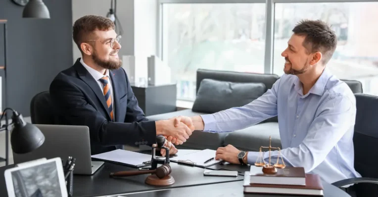 Trust attorney shaking hands with a client in an office with a gavel and legal documents